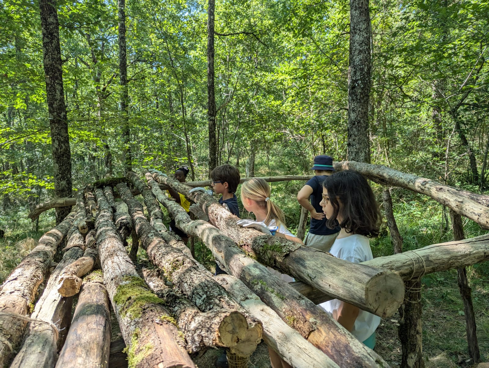 Activité construction cabane favorisant solidarité et entraide entre enfants