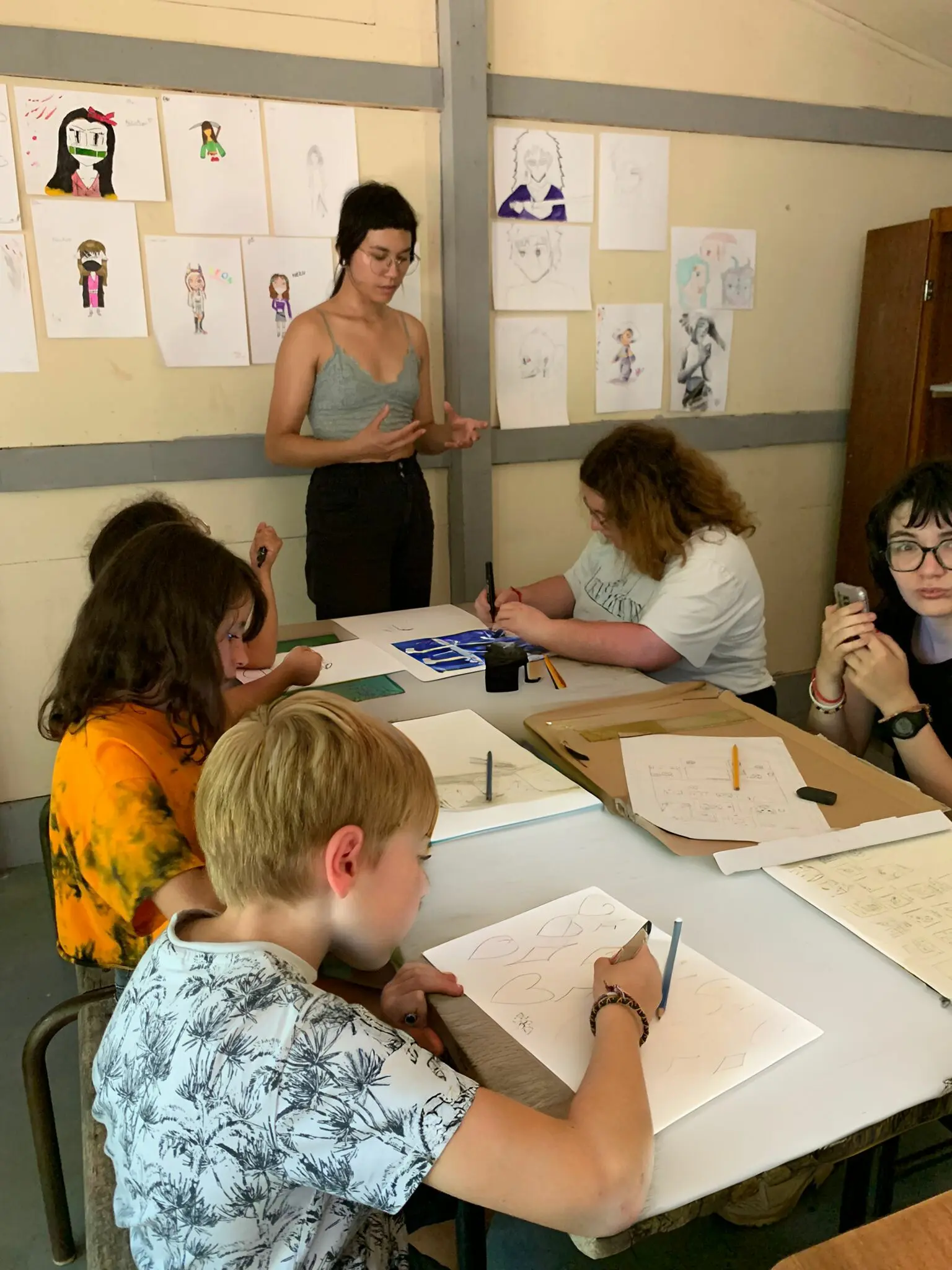 Jeunes participants dessinant des scènes d'action manga durant leur séjour colonie